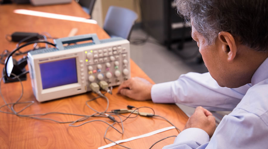 FLCC faculty member adjusting a digital oscilloscope for an electrical signal measurement
